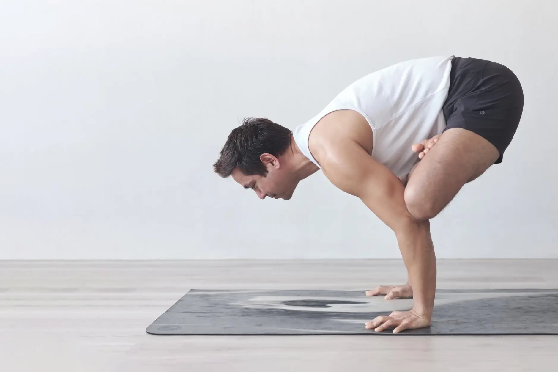 Gajju balancing on his hands in an arm balance on a yoga mat