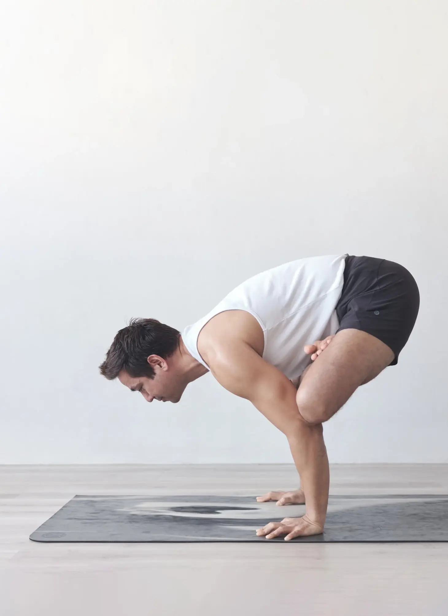 Gajju balancing on his hands in an arm balance on a yoga mat