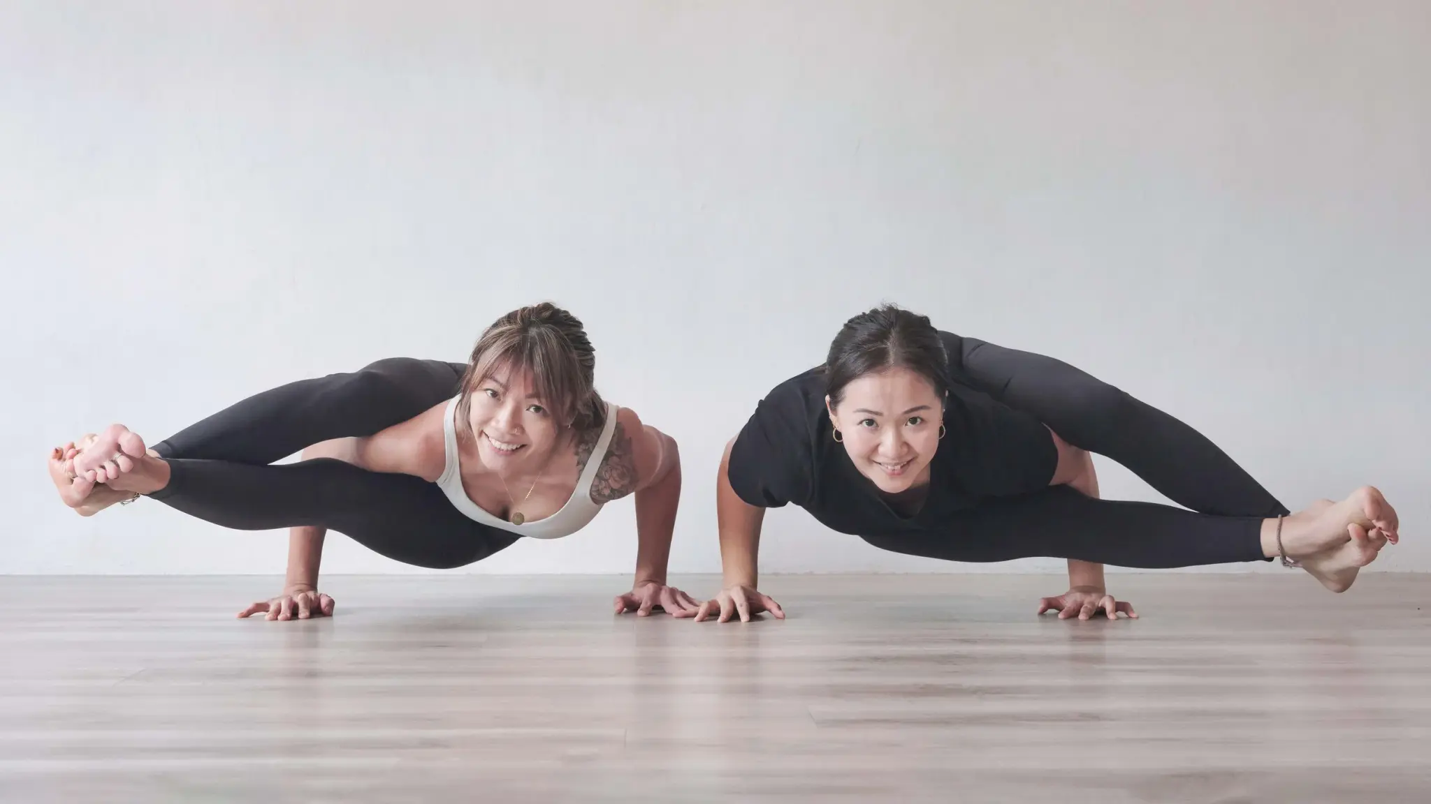 Two practitioners side by side, balancing on their hands in eight-angle pose