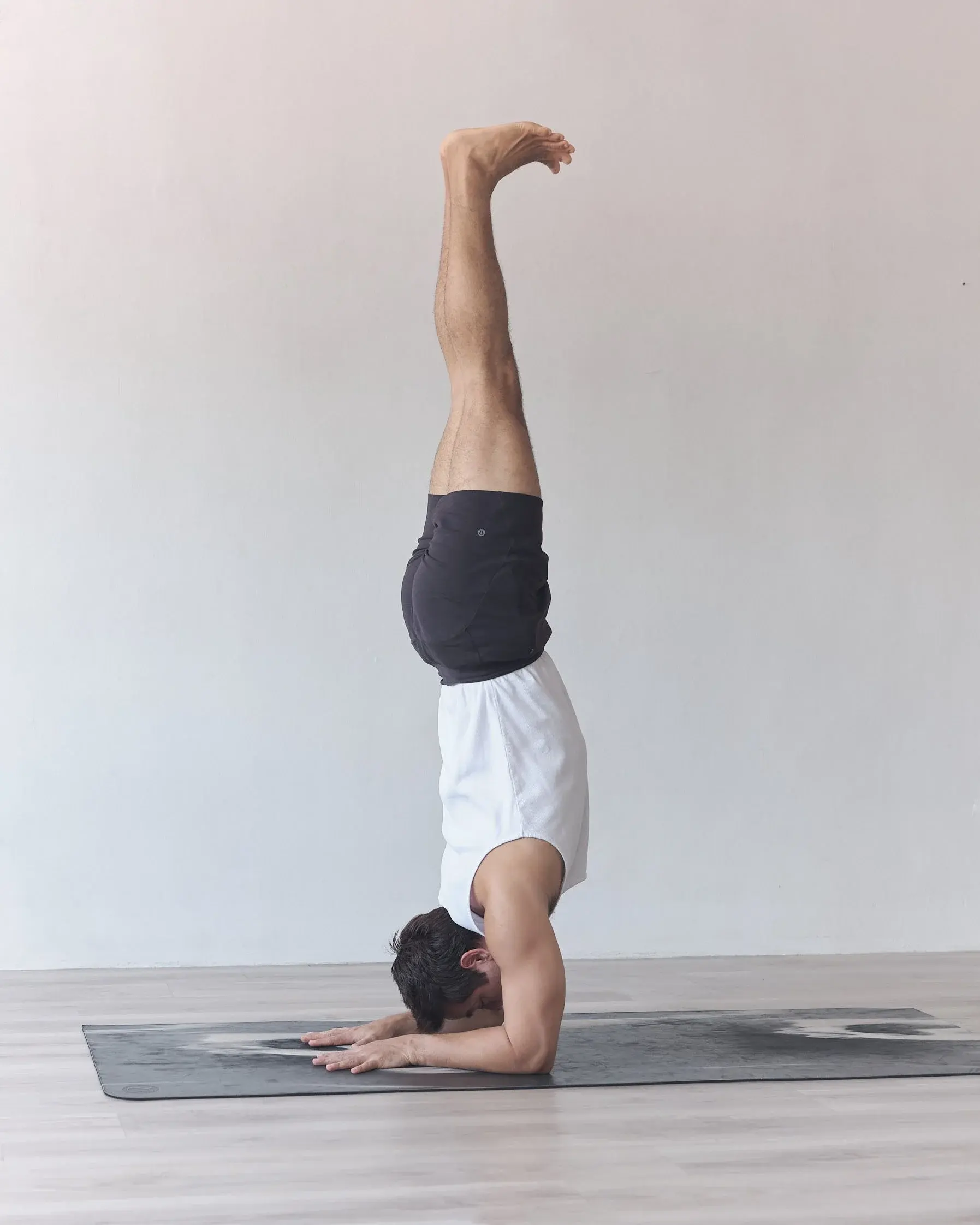 Gajju in a forearm balance, legs straight up above him