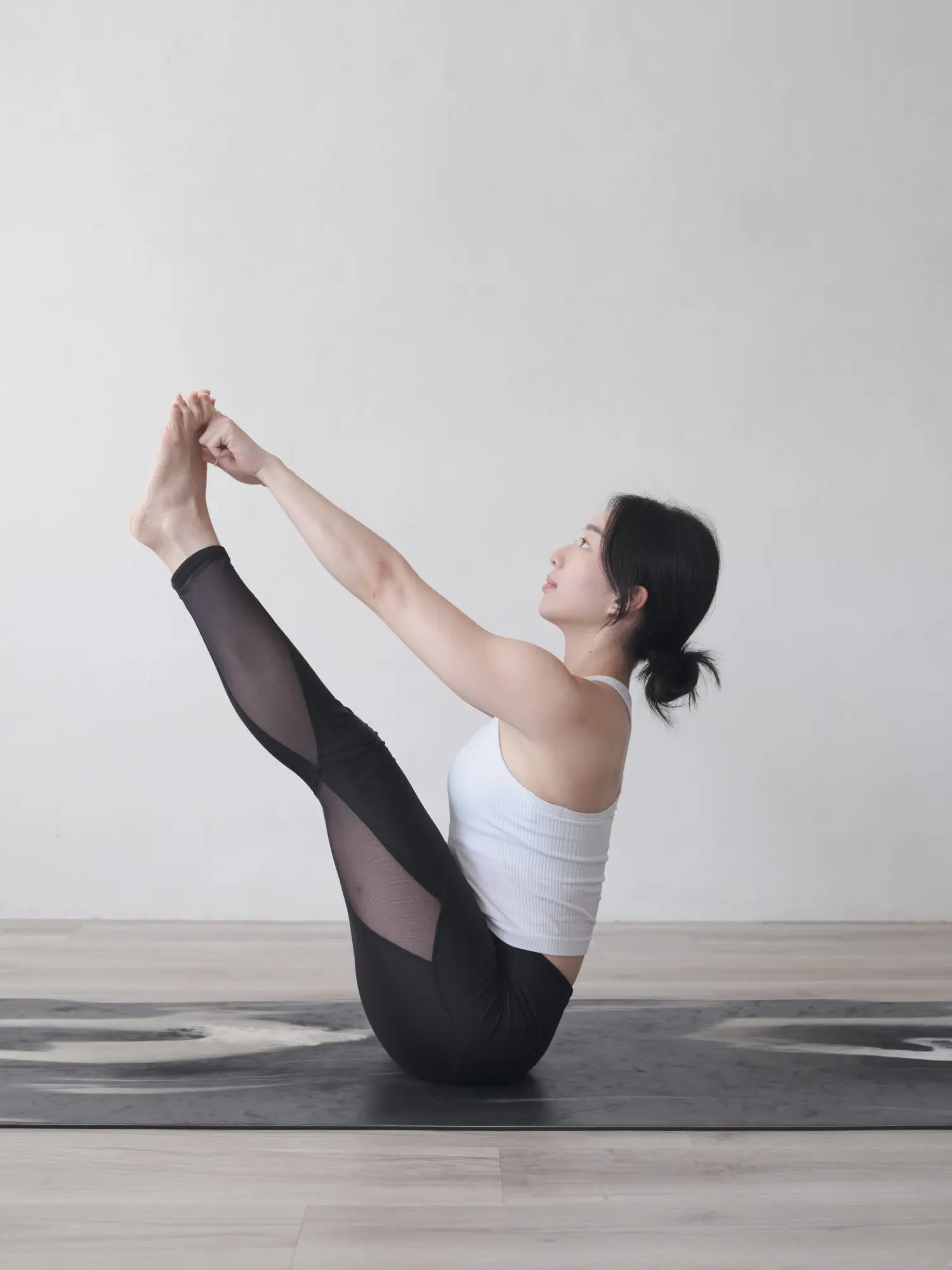Maria balancing in boat pose, legs raised straight and hands holding her feet