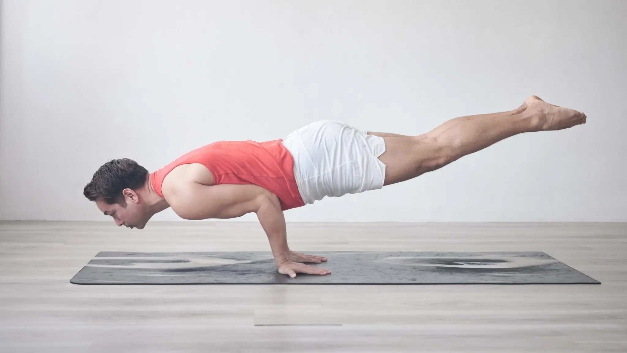 A practitioner balancing horizontally on his hands in peacock pose